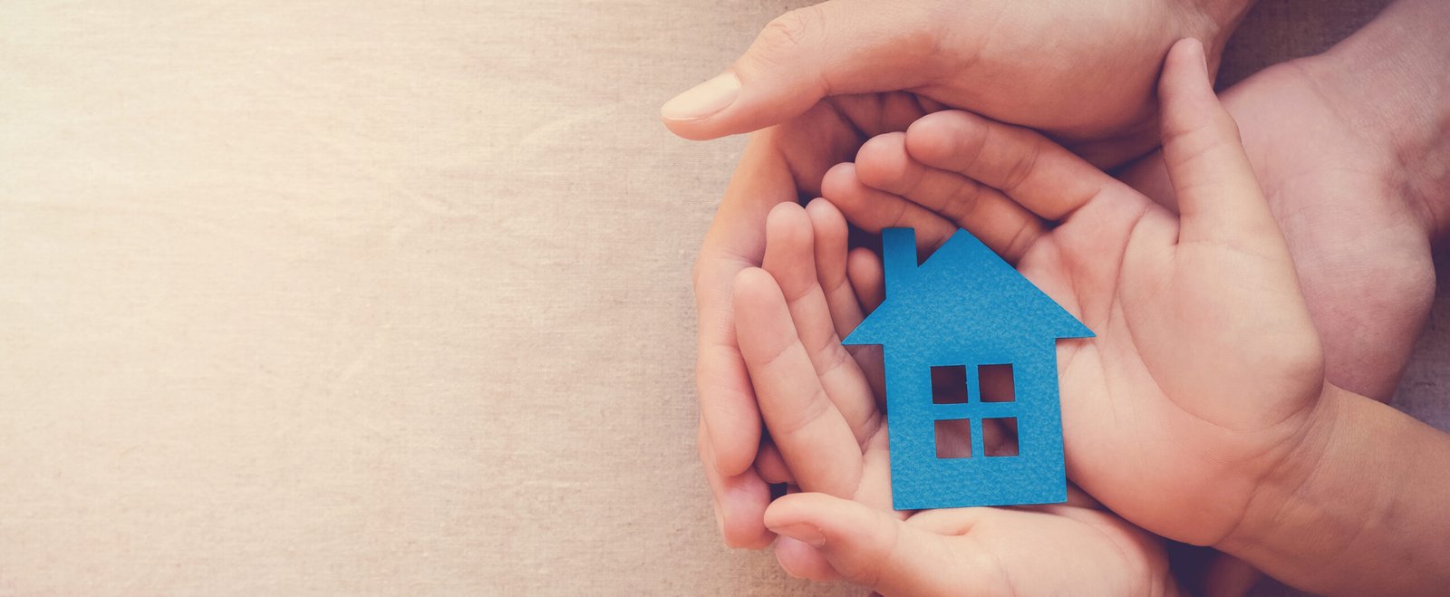 Adult and child hands holding paper house, family home and real